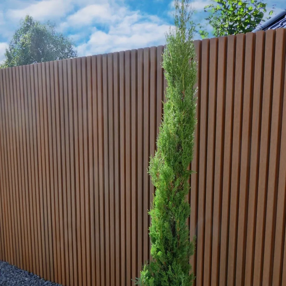 Fiberdeck Gardenwall WEO35 composiet schutting in teakkleur langs een tuinpad van grind