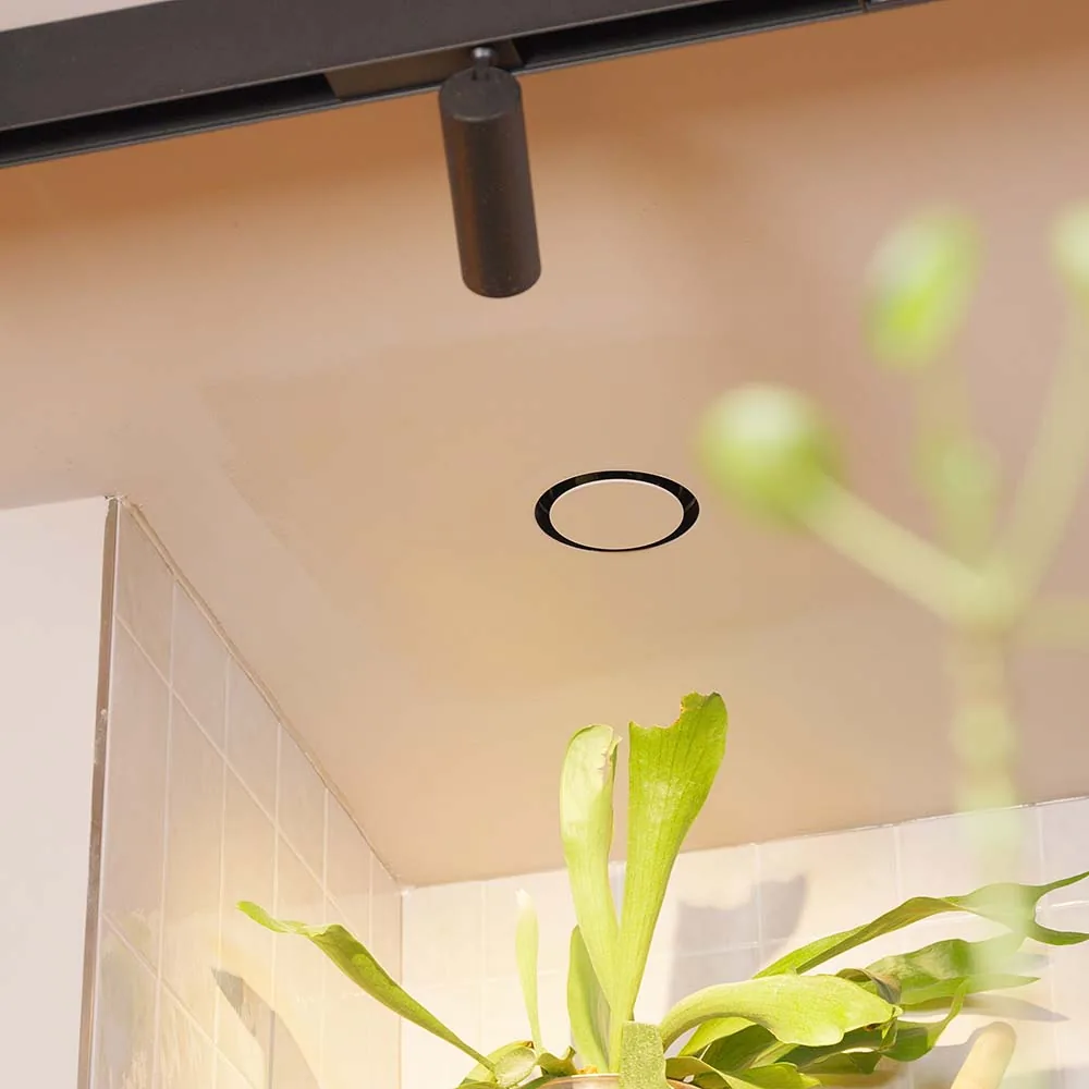 NoShow ventilatierooster vlak weggewerkt in een badkamerplafond, zichtbaar als een dunne ring